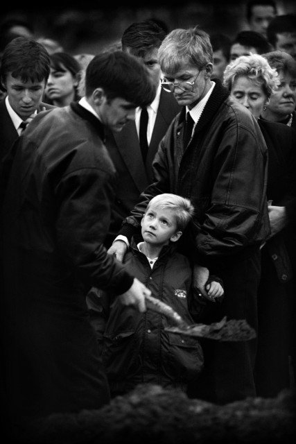 Noord-Ierland, Belfast, oktober 1993. Zilveren Camera 1993.
Begrafenis Mark Rodgers(28). De vuilnisman kwam om het leven doordat extremisten van de protestantse zijde het vuur hadden geopend toen hij de loods wilde openen aan het begin van zijn shift. Hij dook weg onder een vrachtwagen maar een afketsende kogel trof hem in het hart. Hij liet met leven met nog een collega, James Cameron(58). Op de foto zijn familie met centraal zoontje Mark(8).